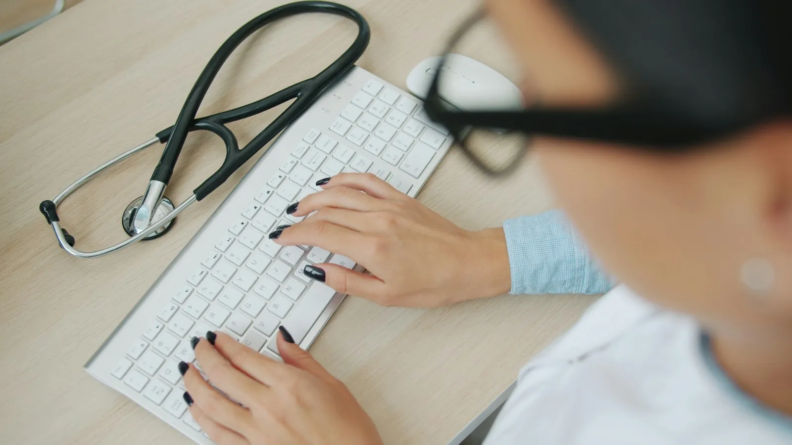 Clinician typing on a keyboard with a stethoscope on the desk, looking for a free CPT test for clinicians