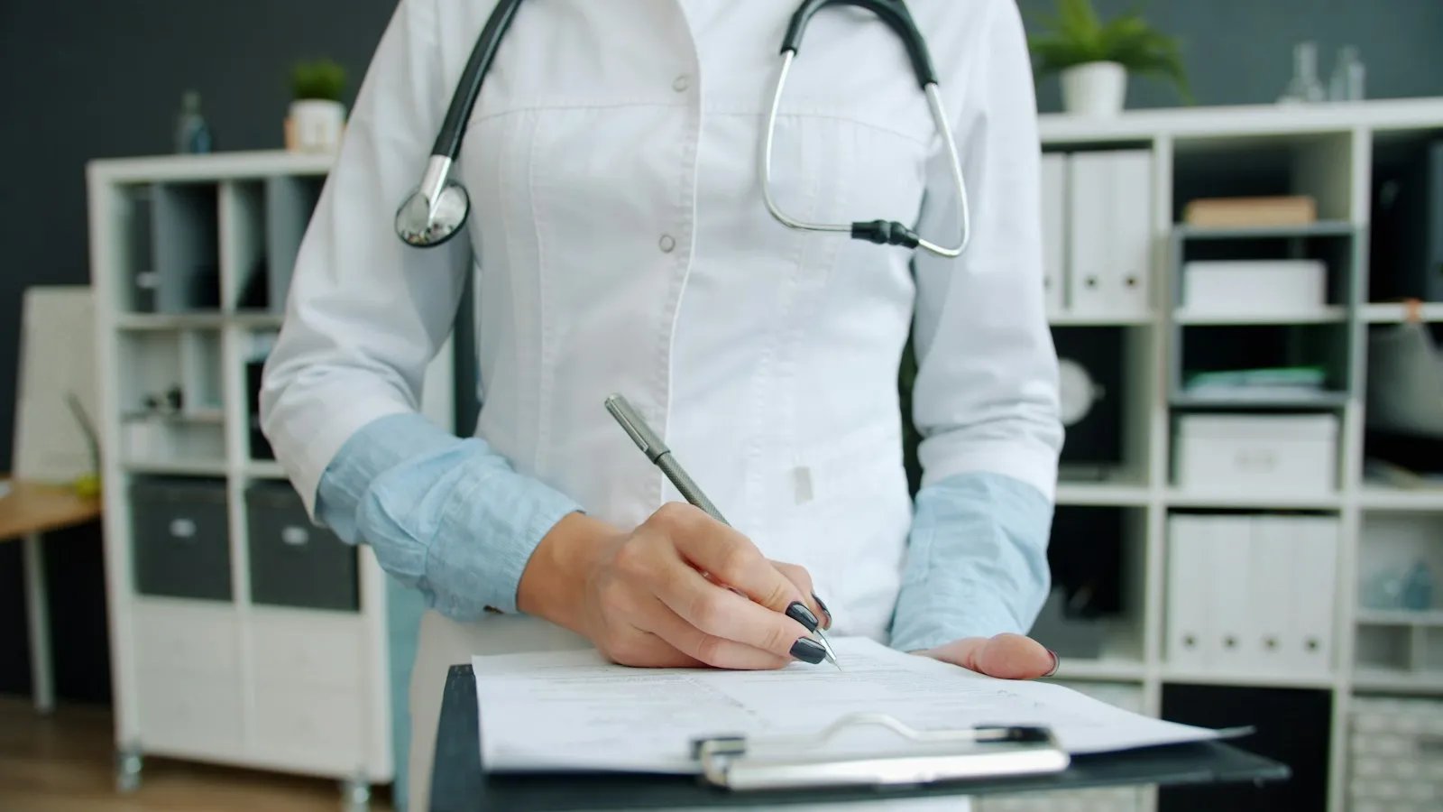 Clinician writing in a patient’s medical record on a clipboard