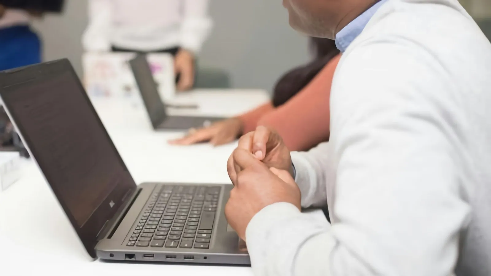 Adult sitting at a table using a laptop computer