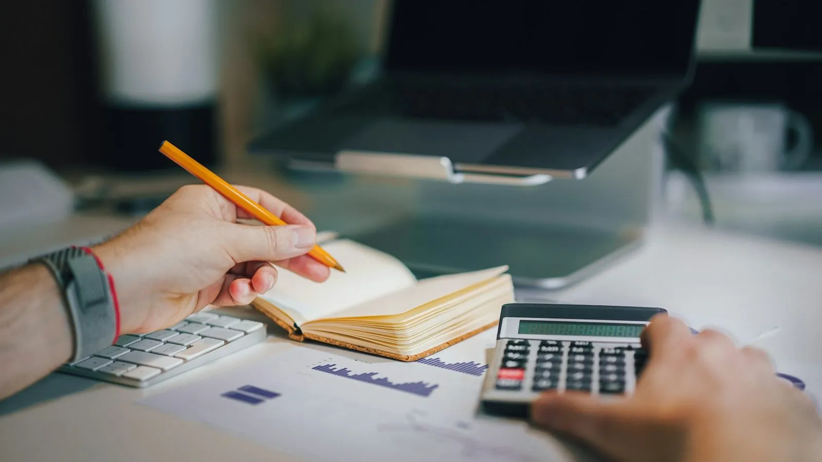 Clinician working through costs with a calculator and notebook at a desk