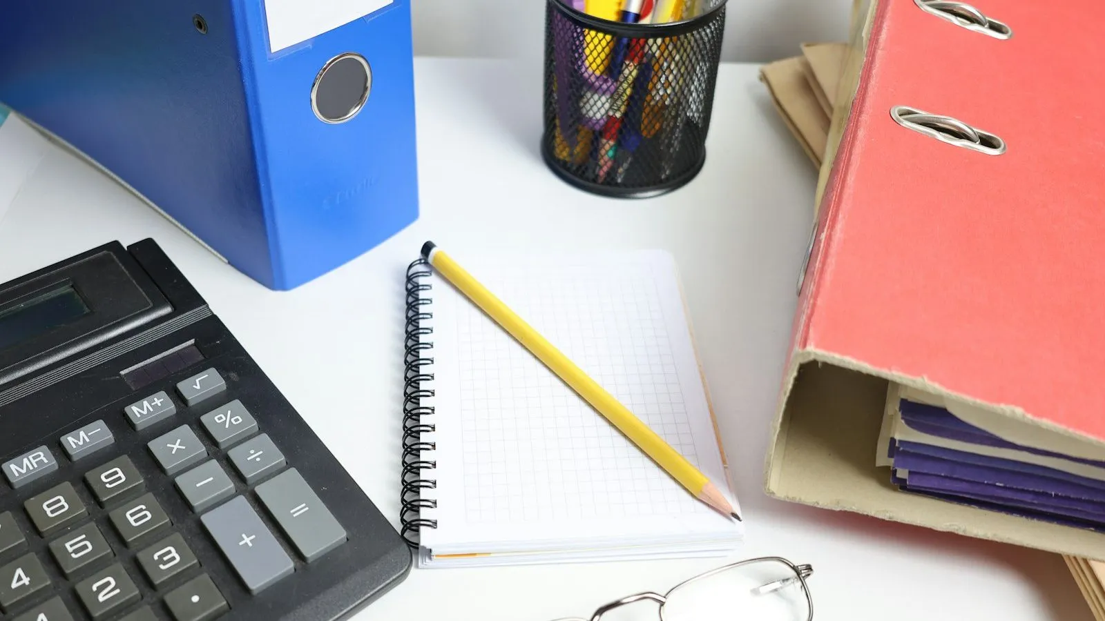 Desk with a calculator, binders, and notebook used for medical billing documentation