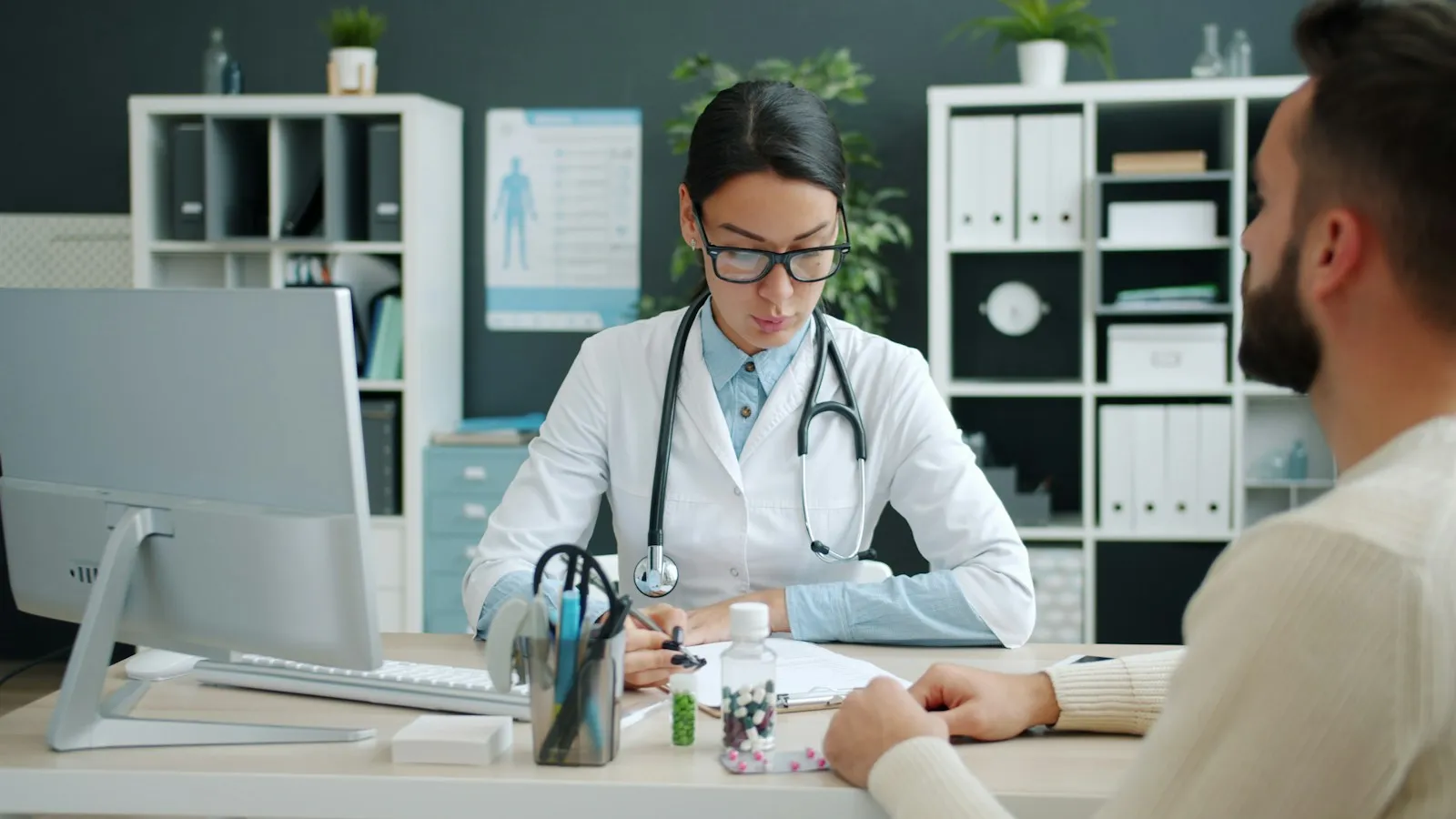 Clinician documenting at a desk during a patient consultation