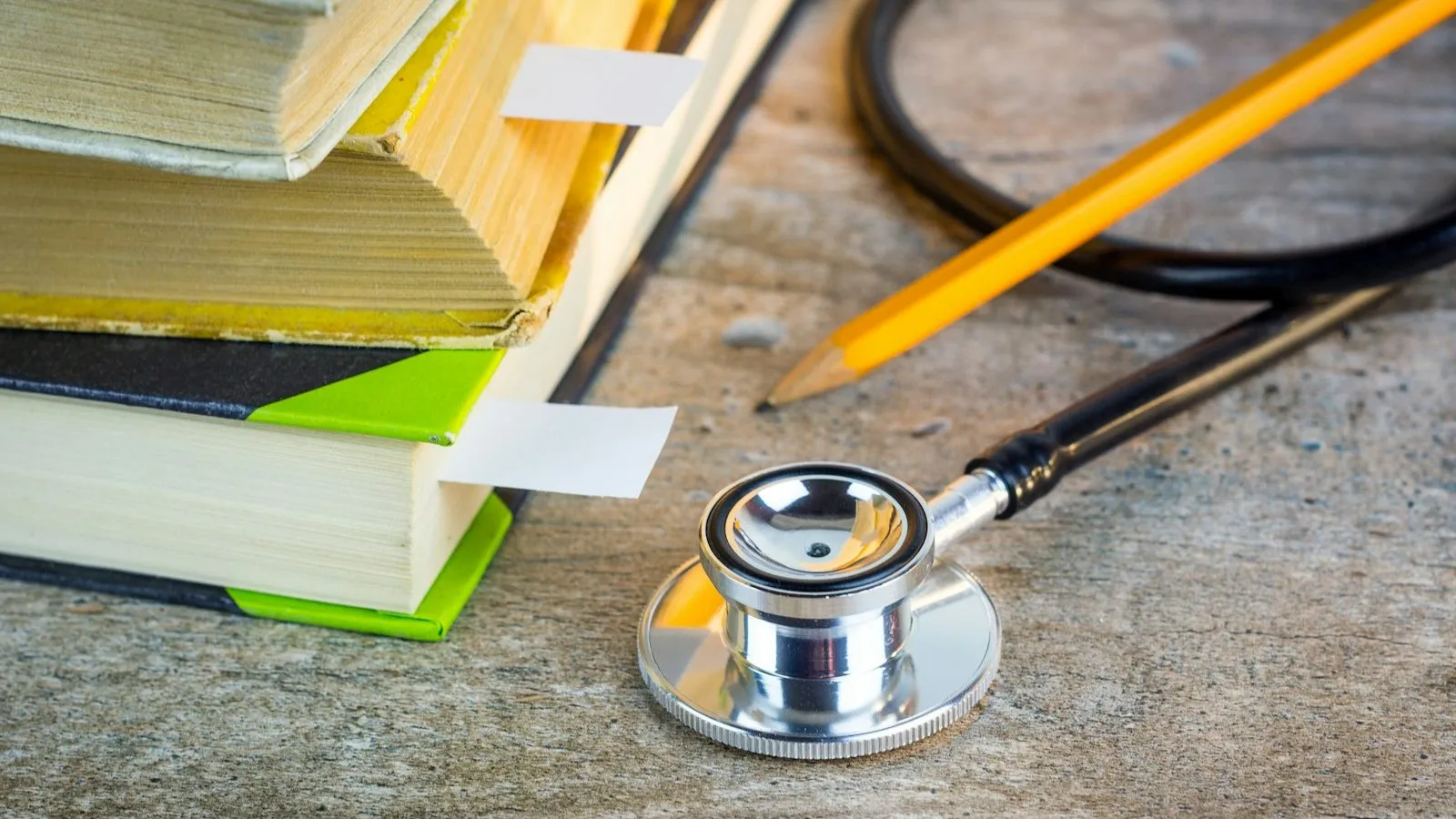 Stethoscope and pencil beside a stack of reference books, representing CPT coding for ADHD tests